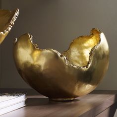 two golden bowls sitting on top of a wooden table next to a bookshelf