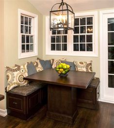 a dining room table with two benches and a bowl of fruit on the bench next to it