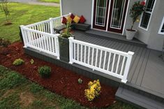 a porch with white railings and flowers on the ground