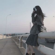 a woman standing on a bridge talking on her cell phone