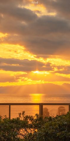 the sun is setting over the ocean and clouds