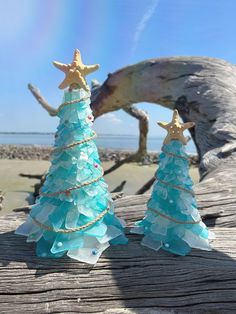 two glass christmas trees sitting on top of a wooden table