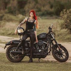 a woman with red hair sitting on a motorcycle