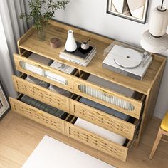 a wooden table with drawers on top of it next to a chair and potted plant