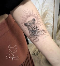 a woman's arm with a tattoo on it and a cheetah in the background