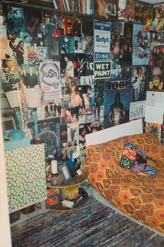 a bedroom with posters on the wall and a bed covered in an orange bedspread