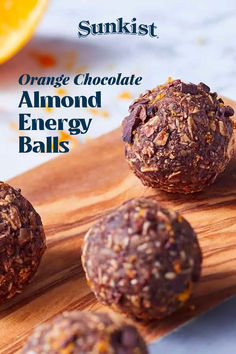 orange chocolate almond energy balls on a wooden cutting board with an orange in the background