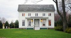 a white two story house sitting on top of a lush green field