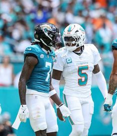 two miami dolphins football players standing next to each other