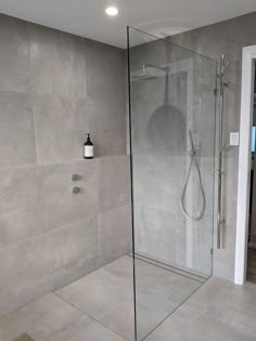 a glass shower door in a bathroom next to a tiled wall and floor with a light on