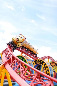 an amusement park ride with a dog on the top and other rides in the background