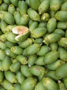 a bunch of unripe green fruit sitting on top of each other in a pile