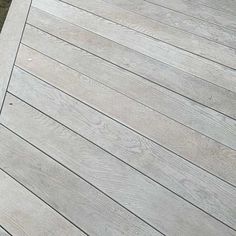 a dog laying on the ground next to a wooden deck with grass in the background