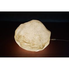 a rock sitting on top of a wooden table next to a light bulb in the dark