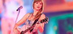 taylor swift performing on stage with her guitar