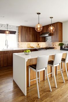 a kitchen with wooden flooring and white counter tops next to an island in the middle