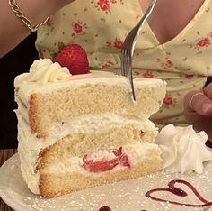 a piece of cake with white frosting and strawberries is being cut by a fork