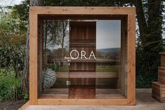 a wooden sauna with the word ora written on it in front of some trees