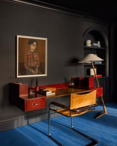 a chair and desk in a room with a painting on the wall behind it,