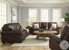 a living room with couches, chairs and a coffee table in front of two windows