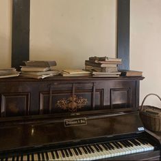 an old piano sitting in front of a mirror with books on it and a basket next to it