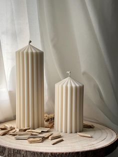 two white candles sitting on top of a wooden table