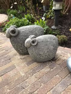 two rock sculptures sitting on top of a brick walkway