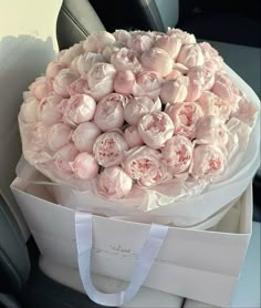 a bouquet of pink roses in a white bag on the back seat of a car