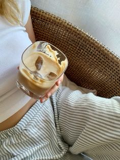 a woman is holding a glass with ice cream in it while laying on her stomach