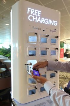 a woman is using her cell phone to pay for the free charging station at an airport