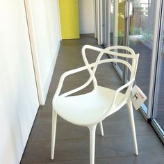 a white chair sitting on top of a tiled floor next to a glass wall and door