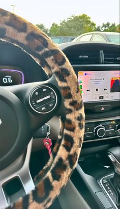 the interior of a car with an animal print steering wheel cover and dashboard controls on