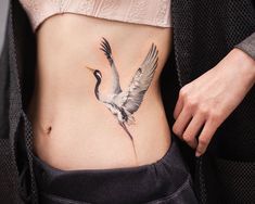 a woman's stomach with a bird tattoo on it