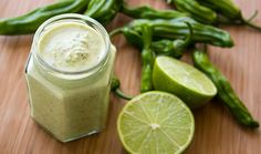 a green smoothie in a mason jar with limes next to it on a wooden table