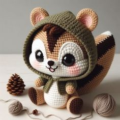 a crocheted animal with a hat and scarf next to some balls of yarn