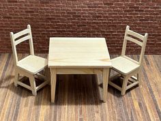 a wooden table and two chairs sitting on top of a hard wood floor next to a brick wall