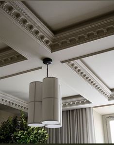 a light fixture hanging from the ceiling in a room with white walls and curtains behind it