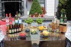 the table is covered with bottles and bowls of fruit, vegetables, and liquors