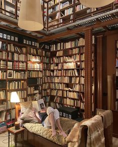 a man laying on top of a couch in front of a book shelf filled with books