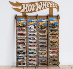 a wooden sign that says hot wheels on the side of a wall with toy cars in it