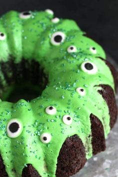 a cake with green frosting and googly eyes on it's face is shown