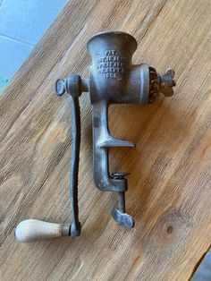 an old metal grinder sitting on top of a wooden table next to a bottle opener