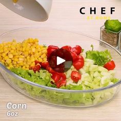 a bowl filled with lettuce, corn and tomatoes on top of a table