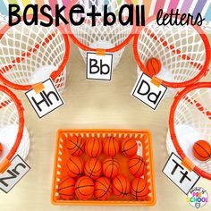 an orange basket filled with basketballs next to some white baskets and letters on the table