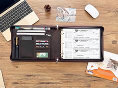 an open leather wallet sitting on top of a wooden table next to a laptop computer