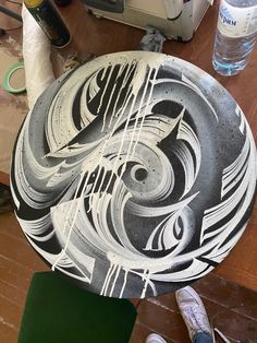 a black and white plate sitting on top of a wooden table next to water bottles