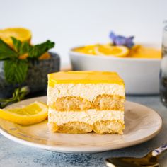 a piece of cake on a plate with lemons and mint leaves in the background