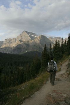 a man with a backpack walking up a trail in the mountains