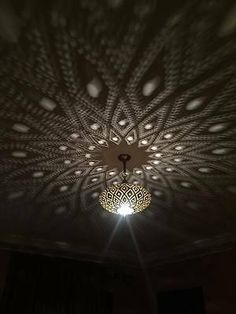 a chandelier hanging from the ceiling in a dark room with light shining on it