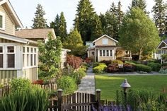 several small houses in the middle of a yard with flowers and trees around them,